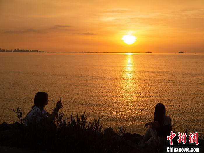 游客在海邊與夕陽美景合影?！×栝?攝