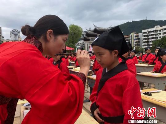 資料圖：在“點朱啟智”環(huán)節(jié)，先生在學(xué)童的額心點上朱砂，寓意孩子從此開啟智慧，目明心亮。曉東 攝