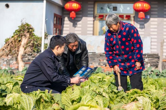 　江蘇省泰州市海陵區(qū)蘇陳派出所民警在蘇陳社區(qū)田間地頭向農(nóng)戶(hù)進(jìn)行普法宣傳(2021年12月4日攝)。新華社發(fā)(湯德宏 攝)