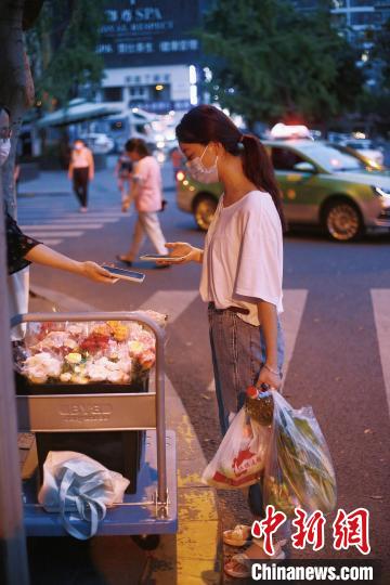 手提兩袋蔬菜的成都市民在選購鮮花?！∈茉L者供圖