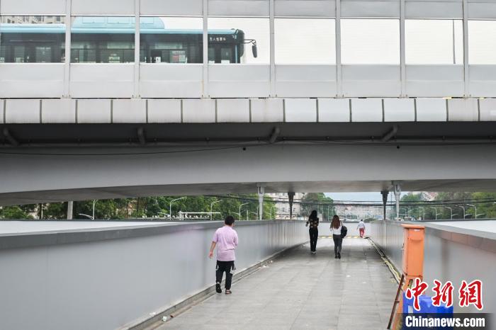圖為市民走在天橋上，公交車從頭頂?shù)缆否傔^?！∨硇拟?攝