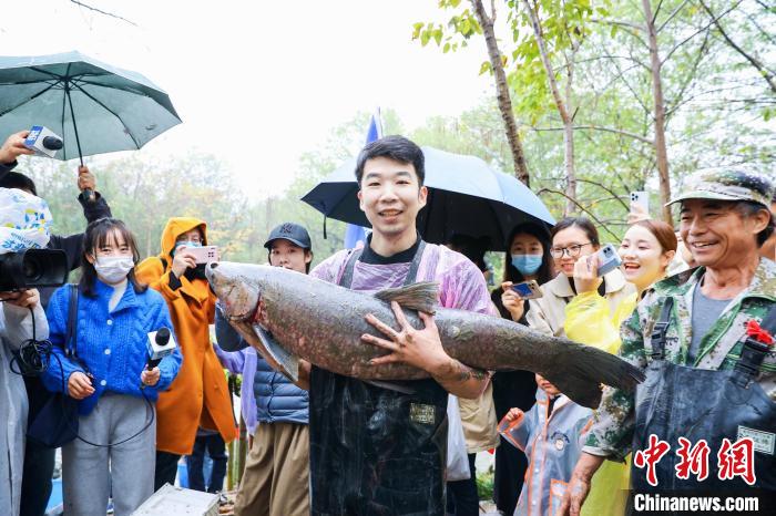 游客王先生抱著抓到的“西溪魚王”向圍觀者展示 西溪濕地 供圖