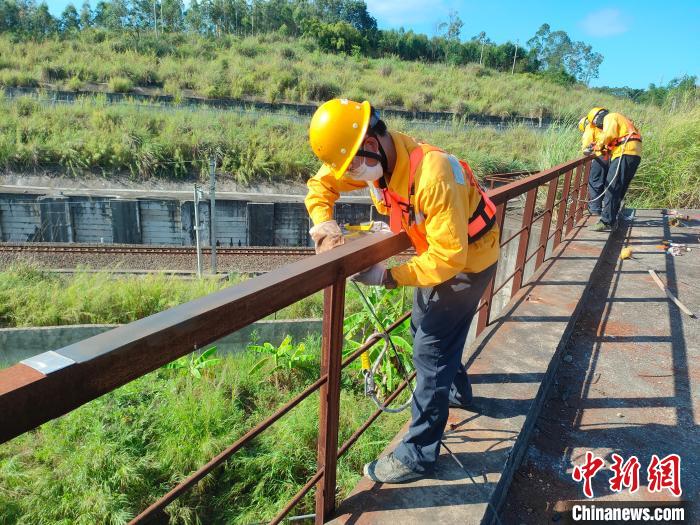 圖為高溫下南寧工務(wù)段橋梁工全副武裝對(duì)鐵路橋梁人行道欄桿打磨除銹?！●T博 攝