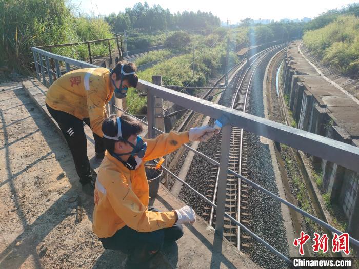 圖為高溫下南寧工務(wù)段橋梁工全副武裝對(duì)鐵路橋梁人行道欄桿打磨除銹?！●T博 攝