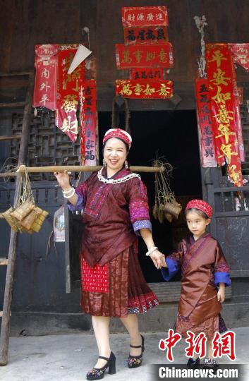 施秉縣楊柳塘鎮(zhèn)陸地坪苗寨苗族女同胞帶著包好的粽粑串門?！》盍?攝