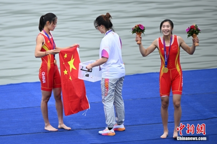 9月24日，杭州第19屆亞運會賽艇女子輕量級雙人雙槳決賽在浙江杭州舉行，中國組合鄒佳琪、邱秀萍以7分06秒78的成績奪冠。這是本屆亞運會的首枚金牌。圖為邱秀萍(左)在頒獎儀式后整理國旗。<a target='_blank' href='/'>中新社</a>記者 王剛 攝