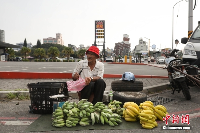 資料圖：臺灣花蓮市區(qū)博愛路早市，商販在街頭擺攤售賣水果，不遠(yuǎn)處是因震傾斜嚴(yán)重的天王星大樓。 中新社記者 楊程晨 攝.jpg